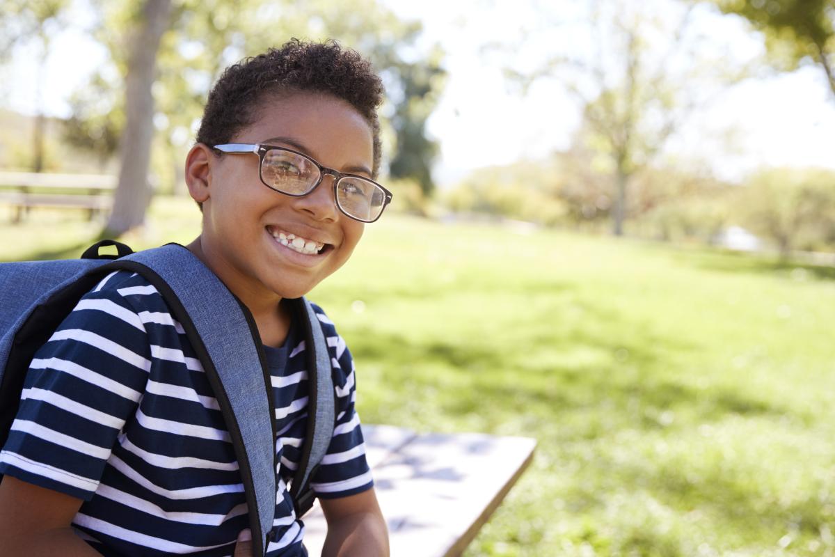 black boy with glasses and bookbag outside