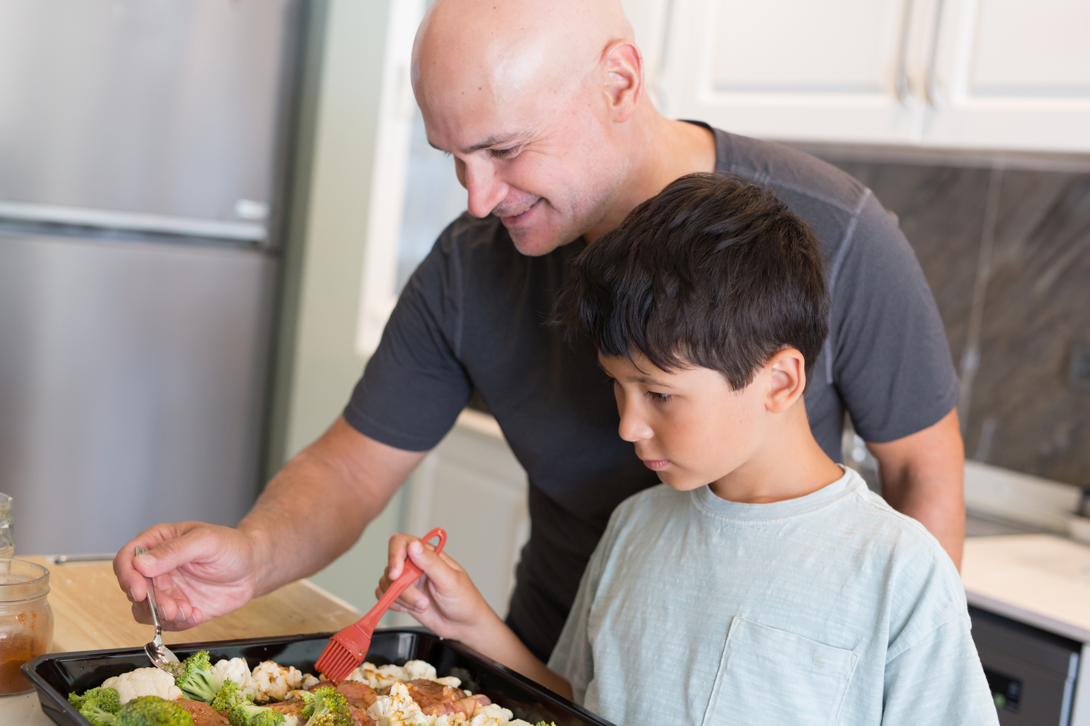 dad and son prepping tray of roasted veggies