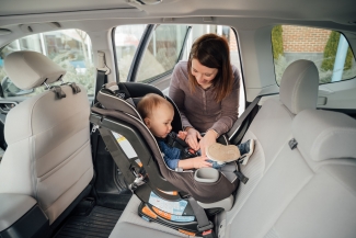 mother putting baby in car seat