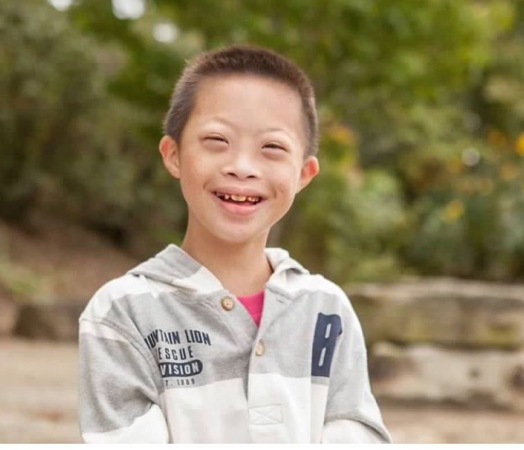 Down syndrome patient Jonah at age 10 outside smiling at the camera