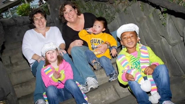 Down syndrome patient Jonah at age 4 with his parents and siblings sitting  on the stairs