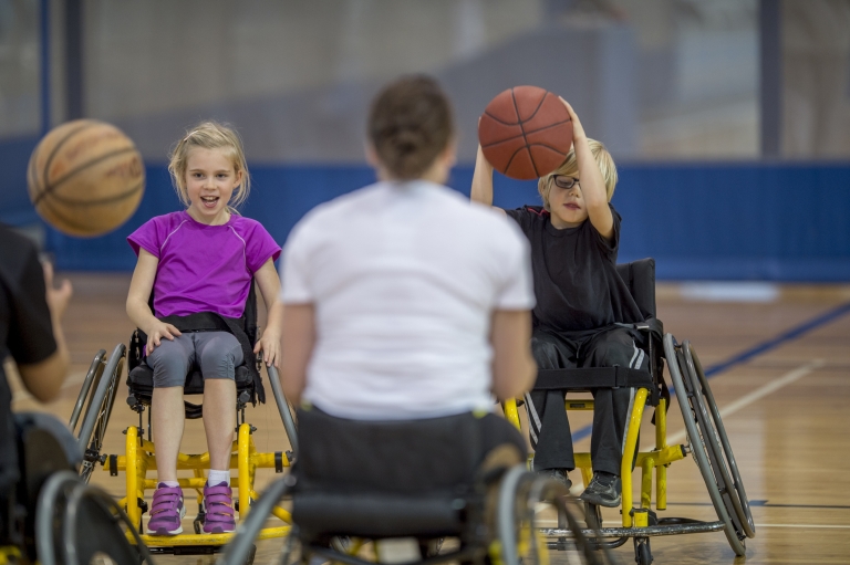 two children in a wheelchair playing basketball