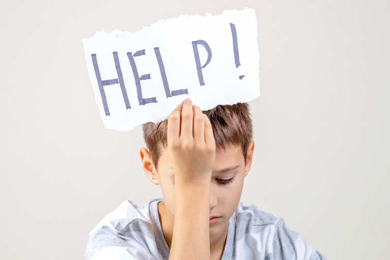 overwhelmed boy holiding "help" sign