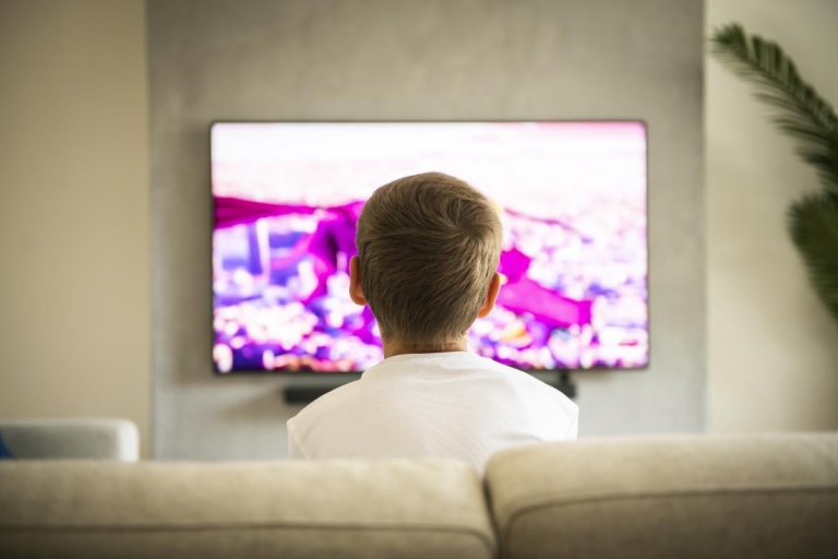 child sitting on couch and watching tv