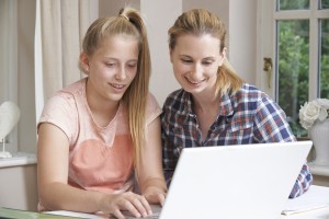 Female Home Tutor Helping Girl With Studies Using Laptop